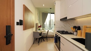 A modern kitchen with a built-in stove, a dining area with a table and chairs, and a view of the city through a large window.