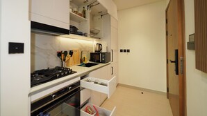 A compact kitchen with a gas stove, microwave, and built-in oven. There is a white countertop, a sink, and a wooden cabinet.