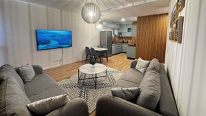 Una sala de estar moderna con un sofá gris, una mesa de centro y un televisor montado en la pared.
