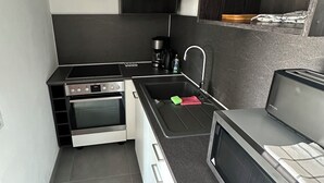 Eine kompakte Küche mit einbauendem Ofen, einer Mikrowelle und einer Kaffeemaschine.
