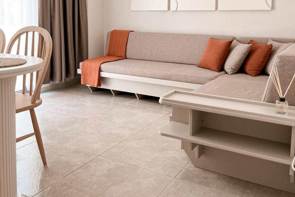 Ein modernes Wohnzimmer mit einer Couch, einem Esstisch mit Stühlen und einer Pendelleuchte.