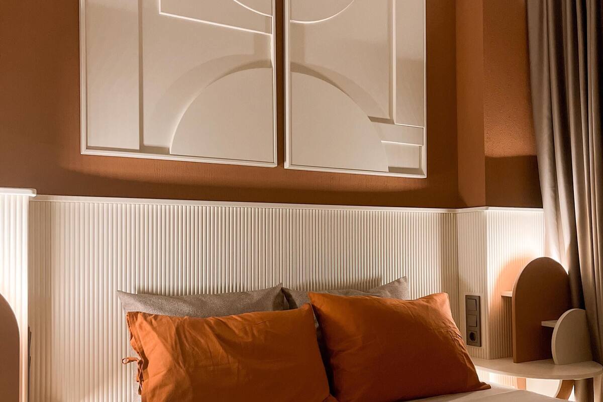 Ein Hotelzimmer mit einem großen Bett, einem vertikal gemusterten Kopfteil und zwei Wandleuchten.