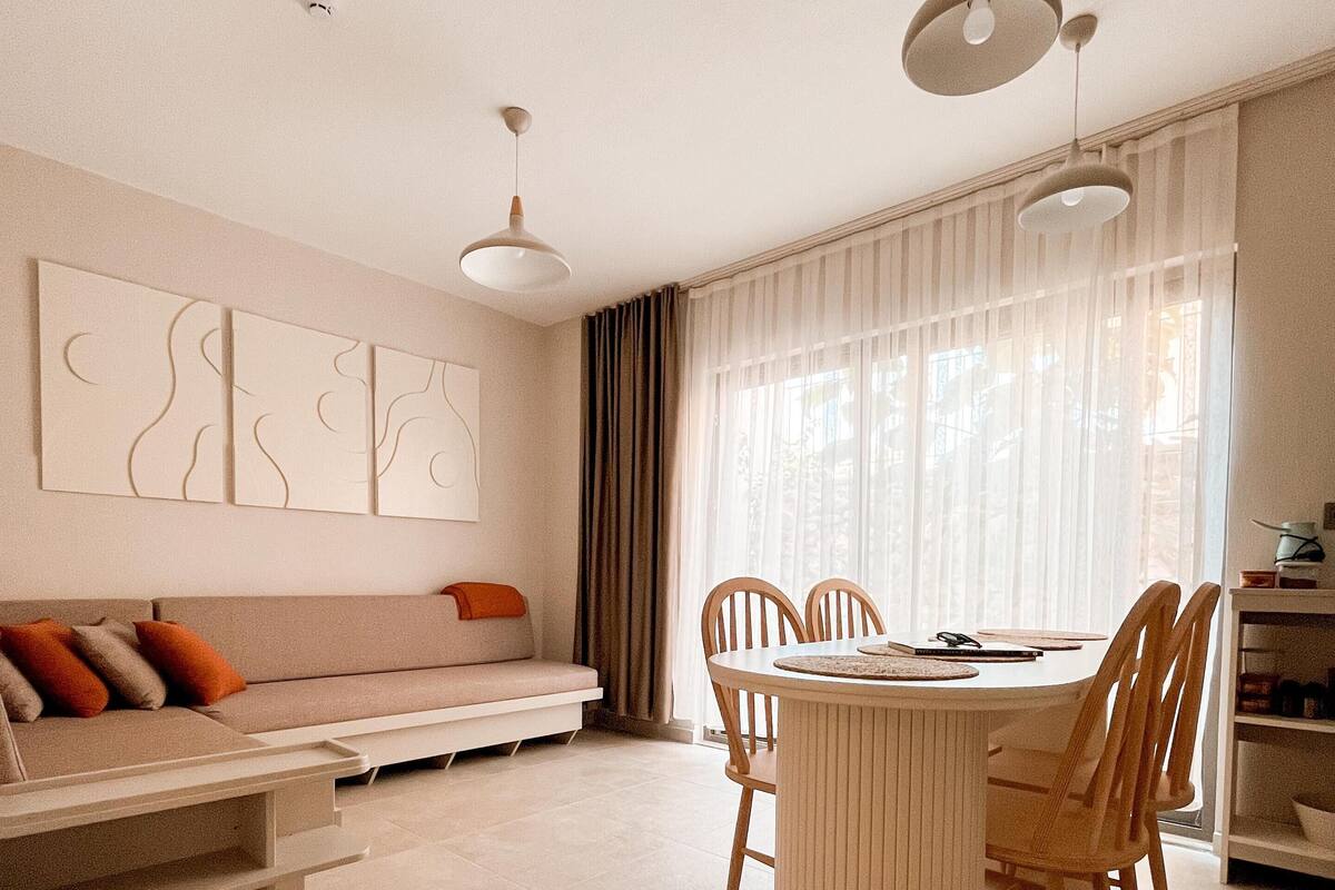 Ein modernes Wohnzimmer mit einer Couch, einem Esstisch mit Stühlen und abstrakten Wandbildern.
