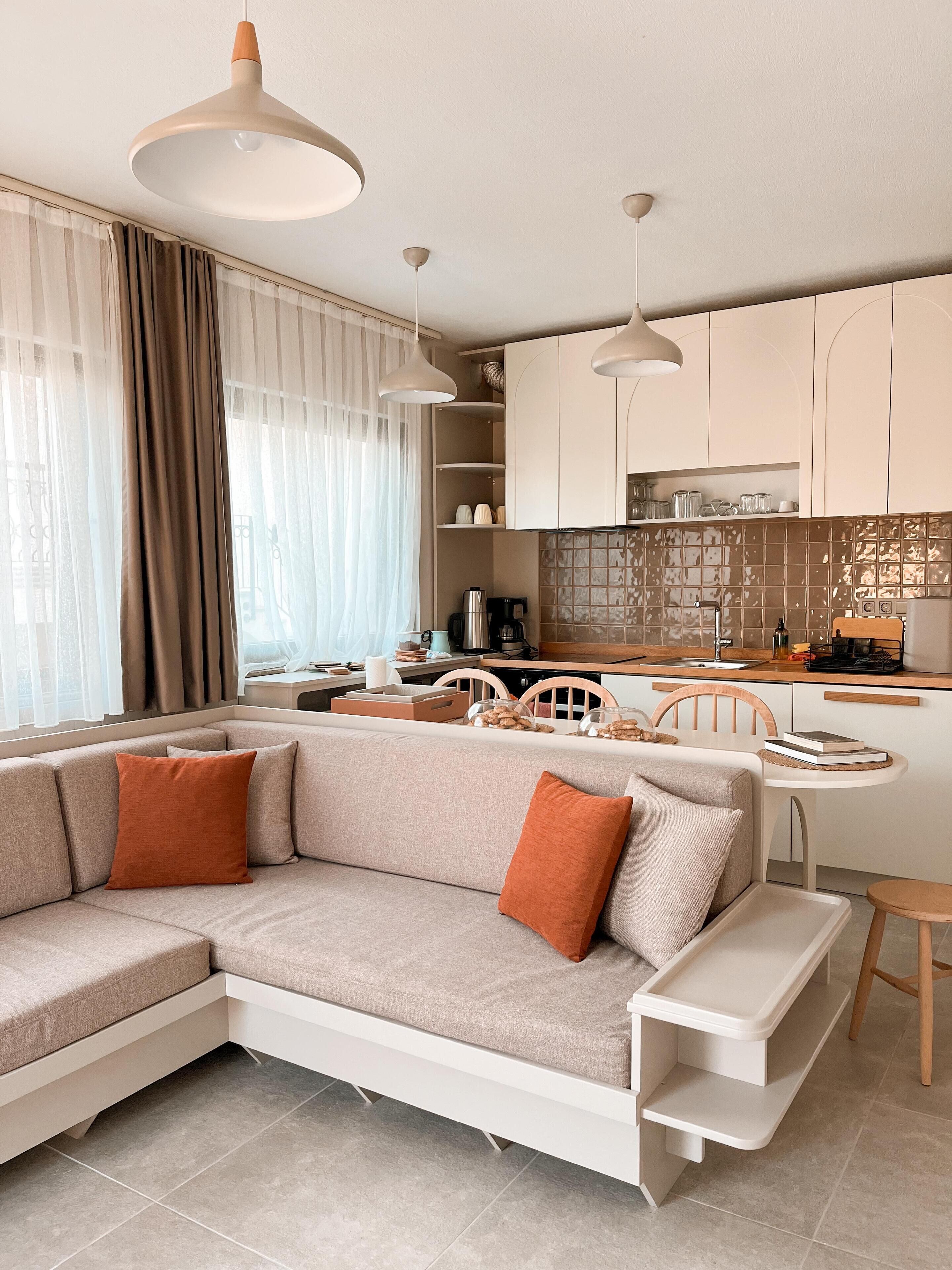 A modern living room with a sectional sofa, a dining area, and a kitchen.
