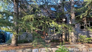 Un mur de pierre, une terrasse en bois et une maison avec une cheminée.
