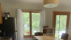 Une cuisine avec des armoires en bois, un four encastré, un évier et un coin repas comprenant une chaise et une table.