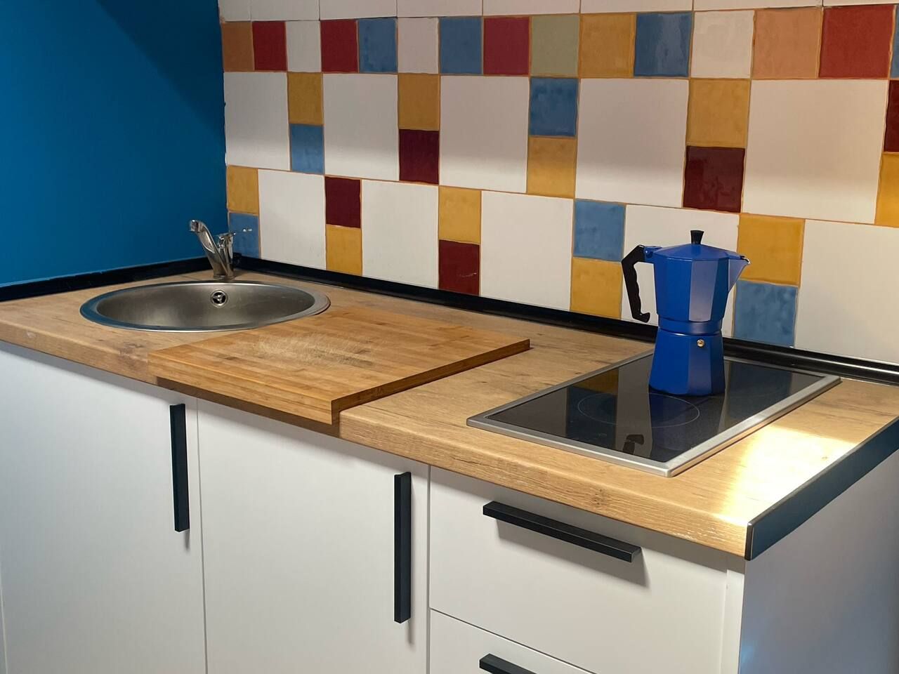 Een keuken met een houten aanrecht, een spoelbak en een blauwe koffiezetapparaat.