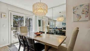 A dining area with a wooden table, black chairs, and a woven chair. There is a decorative bowl on the table.