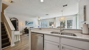 A modern kitchen with a built-in dishwasher, a large window, and a pendant light.