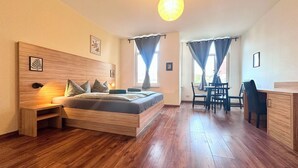 A modern bedroom with a wooden bed, bedside tables, a desk, and a chair. - Appartementhaus am Dom  (Halle (Saale))