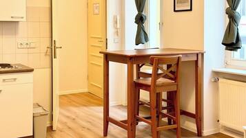 Una cocina compacta con una mesa y silla de madera, un armario blanco y un radiador.
