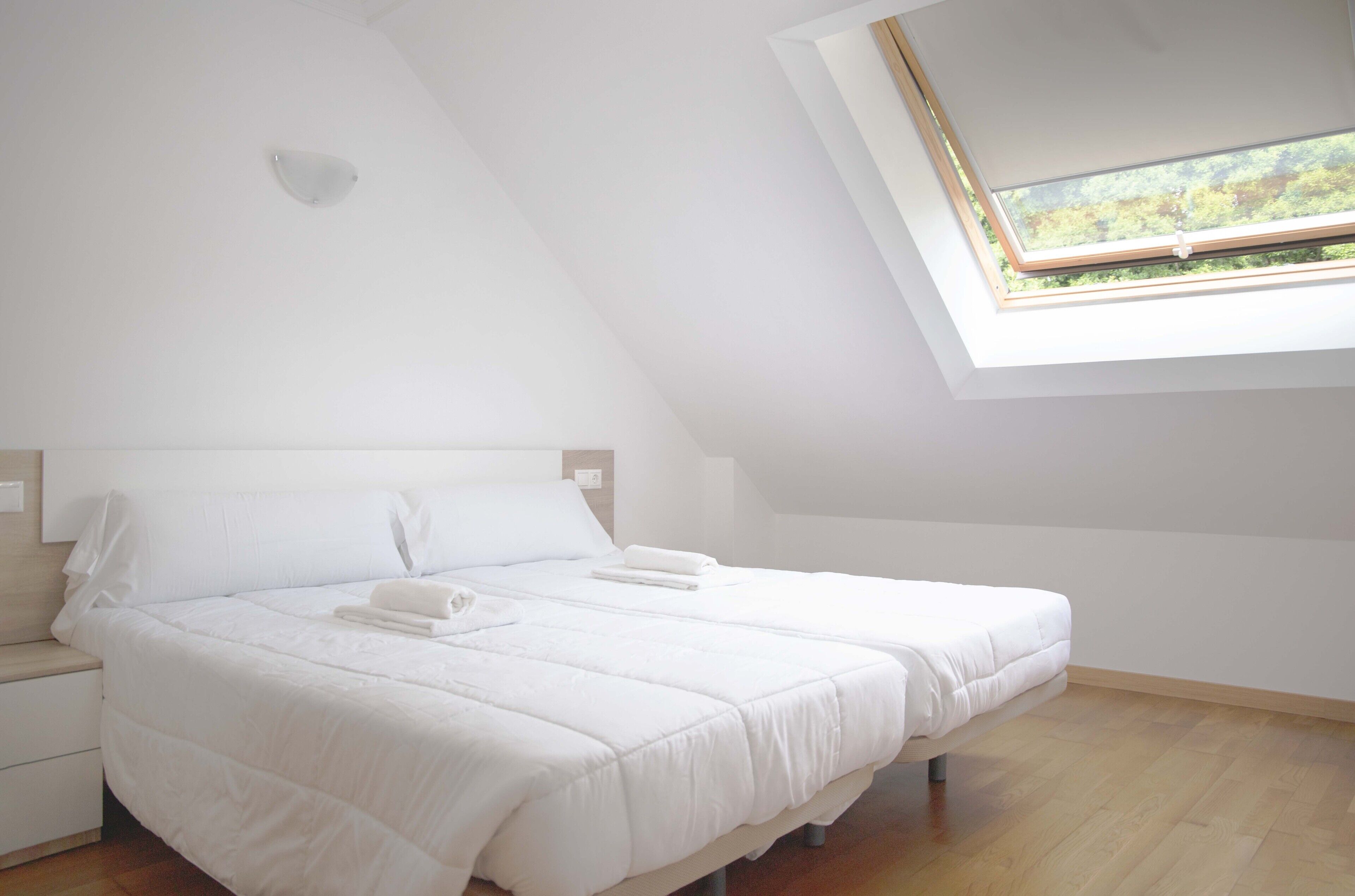 A bedroom with a sloped ceiling and a skylight.