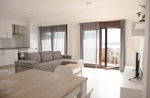 A modern apartment with a kitchen, a dining area, a living room with a sofa, and a balcony with a view. - APARTAMENTOS TERRAMAR BOIRO With sea views in the Ría de Arousa (Galicia) (Boiro)