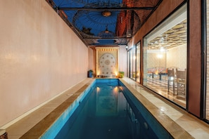 A swimming pool with a tiled edge, a decorative ceiling, and a view of an adjacent room with a checkered floor. - Spacious 5-bedroom villa in charming Marrakech with WiFi, AC, Private Pool (Marrakech)