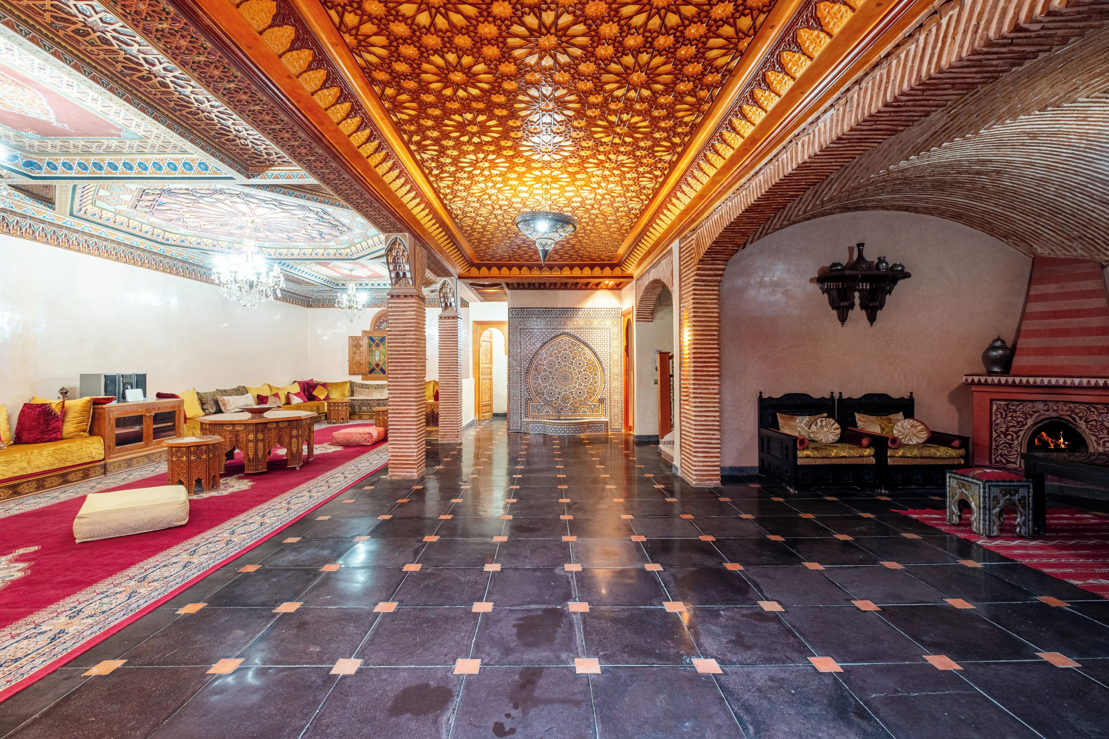 Un hall d’entrée spacieux, doté d’un plafond orné de motifs, d’une moquette rouge et de meubles de style traditionnel.