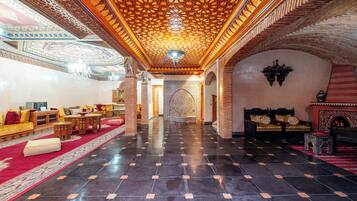Un hall d’entrée spacieux, doté d’un plafond orné de motifs, d’une moquette rouge et de meubles de style traditionnel.