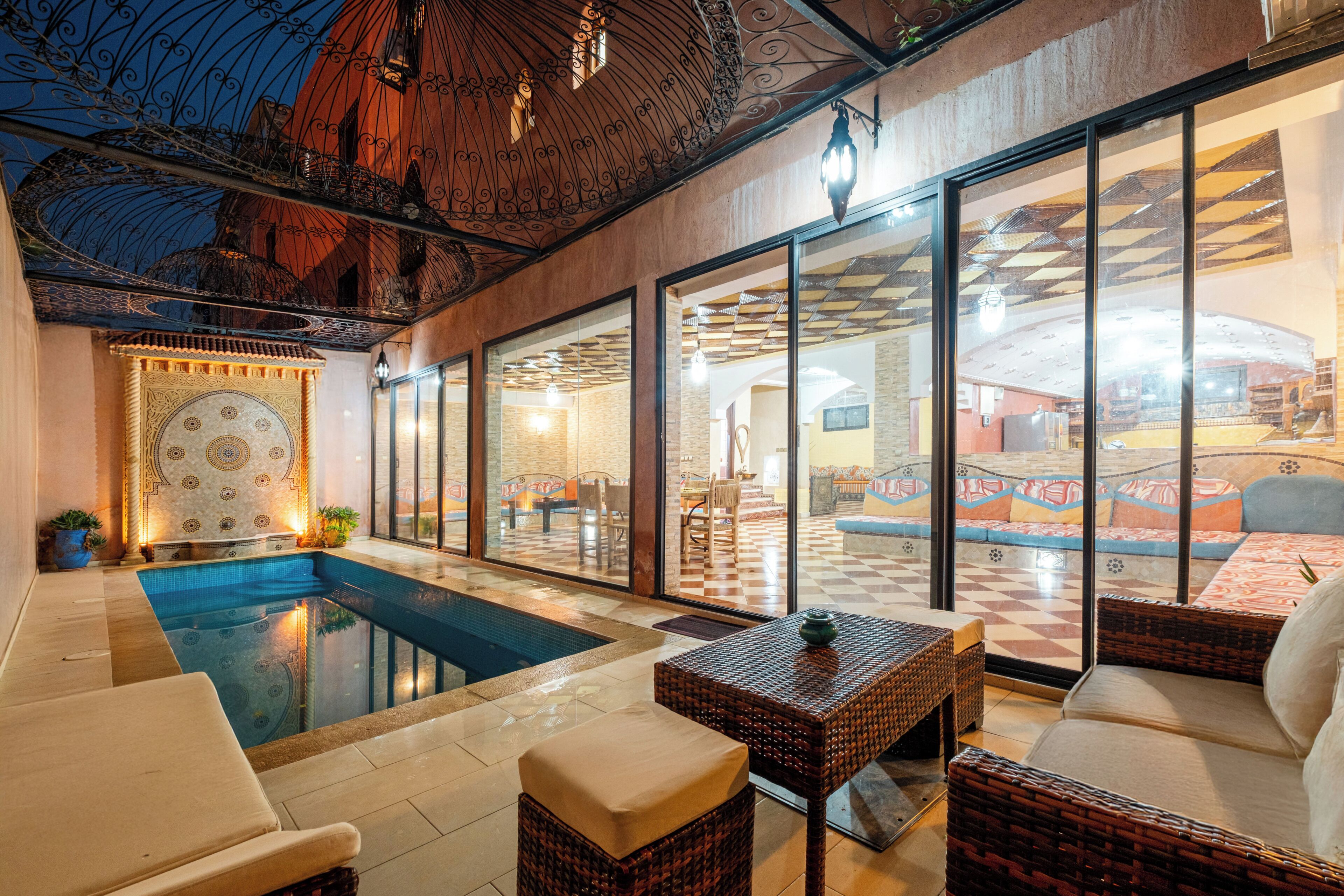 Un espace aménagé au bord de la piscine, comprenant une piscine, des chaises longues et un coin repas avec des meubles en osier.