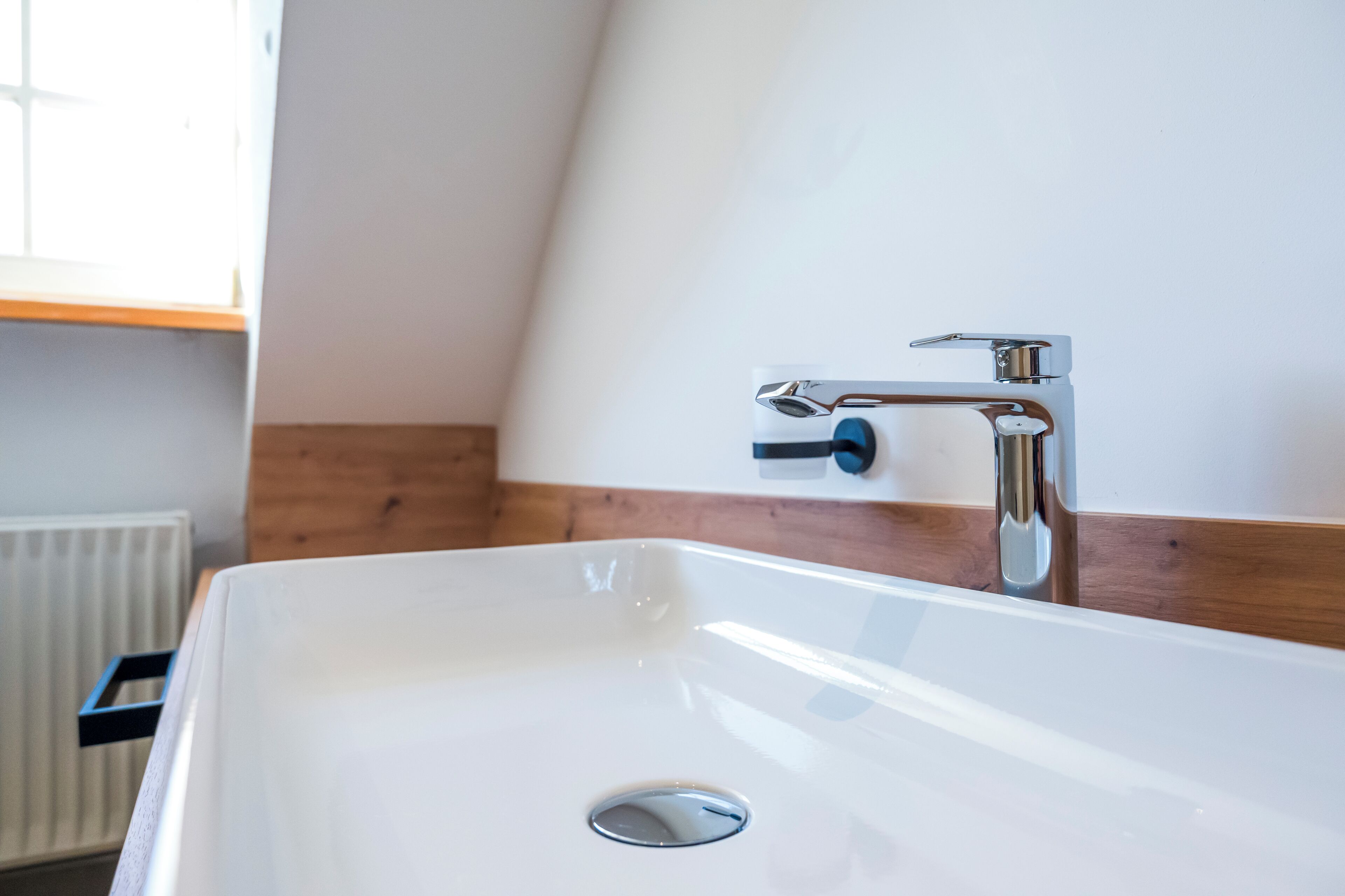 Une salle de bain moderne avec un lavabo blanc, un robinet chromé et un lambris en bois sur le mur.
