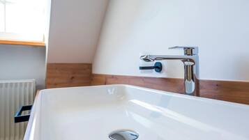 Une salle de bain moderne avec un lavabo blanc, un robinet chromé et un lambris en bois sur le mur.