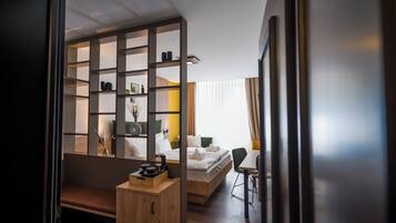 Una habitación de hotel moderna con una cama, un escritorio, una silla y una estantería empotrada con diversos objetos.