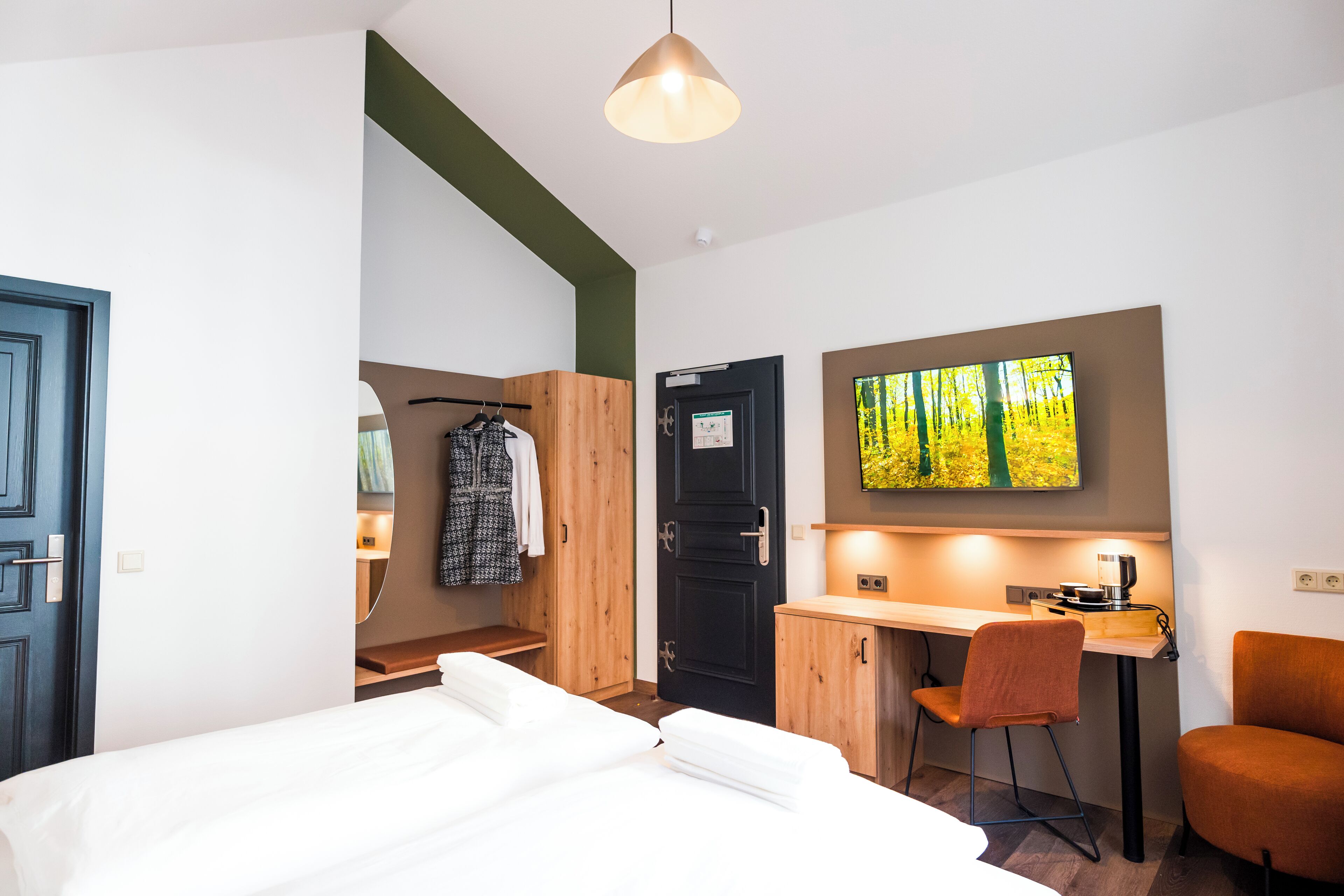 A modern hotel room with a bed, a desk, and a chair.