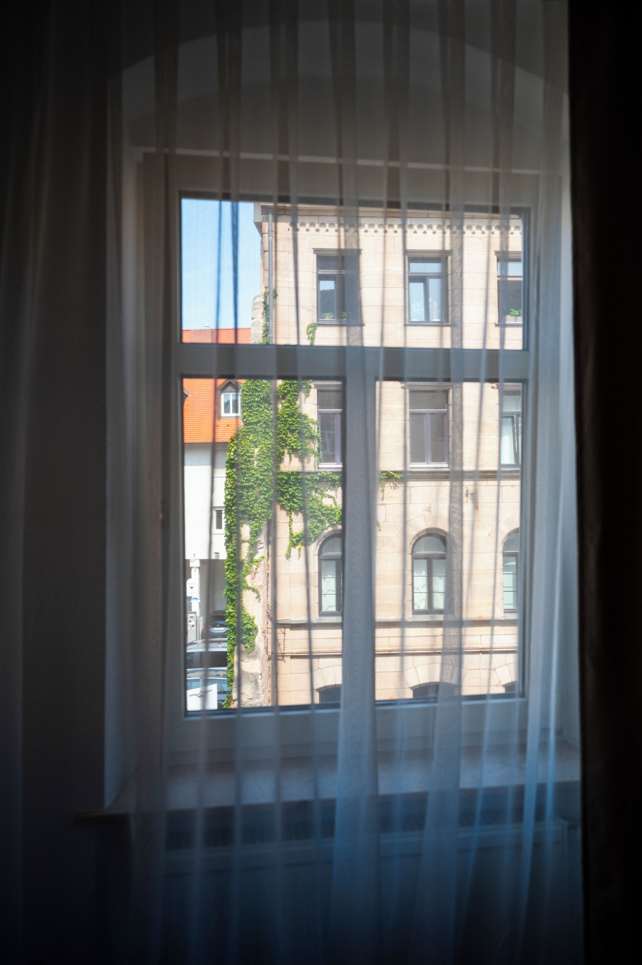 A window with a view of a building with multiple windows and a brick facade.