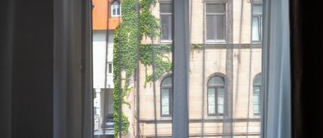 Una ventana que ofrece vistas a un edificio con múltiples ventanas y fachada de ladrillo.