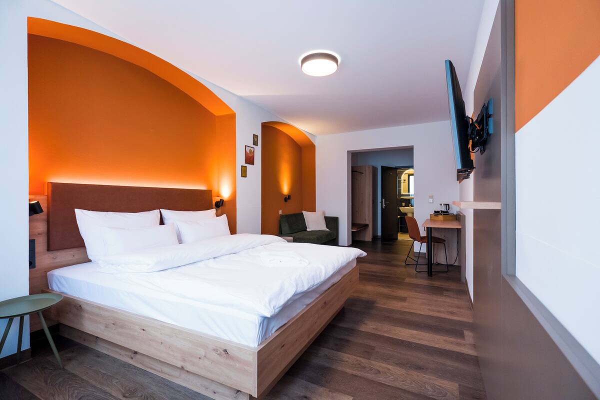 Una habitación de hotel moderna con una cama de madera, un escritorio y una silla.