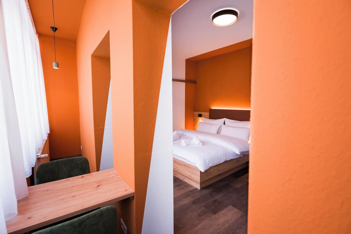 Una habitación de hotel compacta con una cama de madera, un escritorio pequeño y una silla.