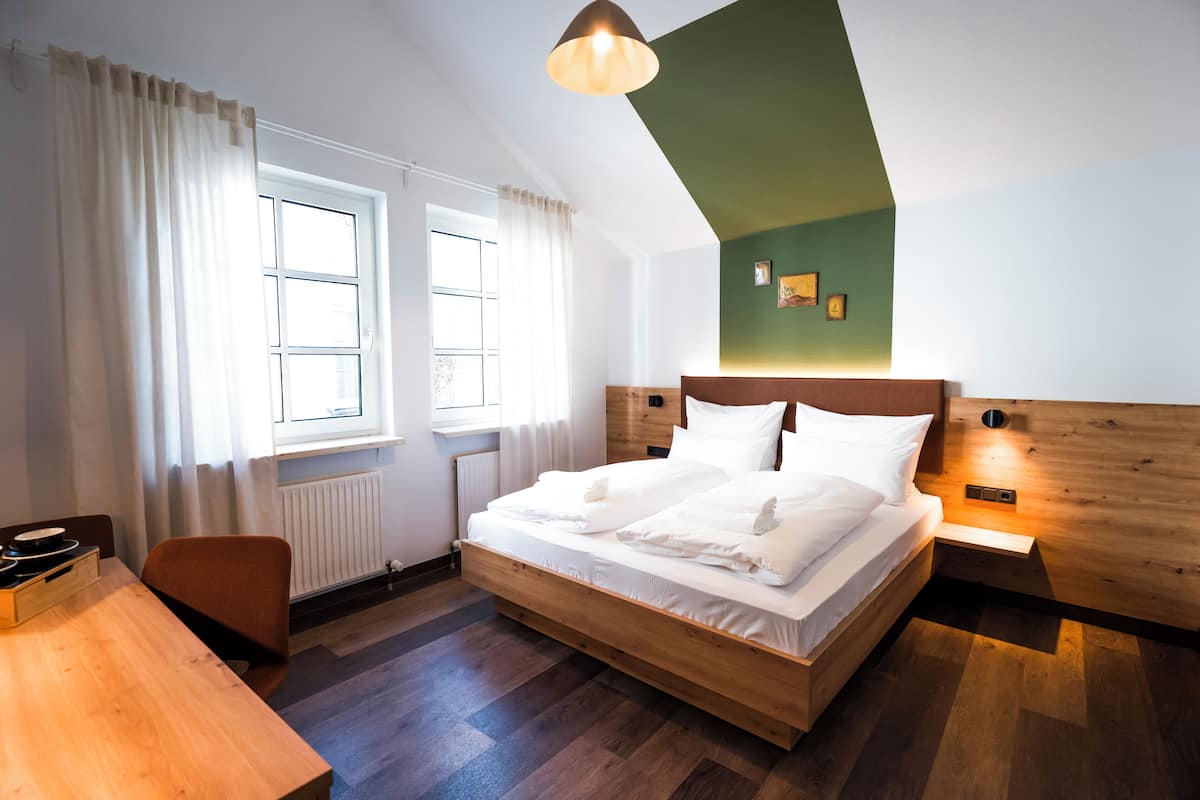 Un dormitorio moderno con una cama de madera, un escritorio y un ventanal con cortinas.