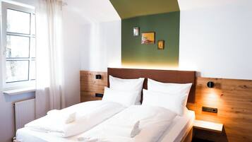 Un dormitorio moderno con una cama de madera, una pared de acento verde y una lámpara colgante.