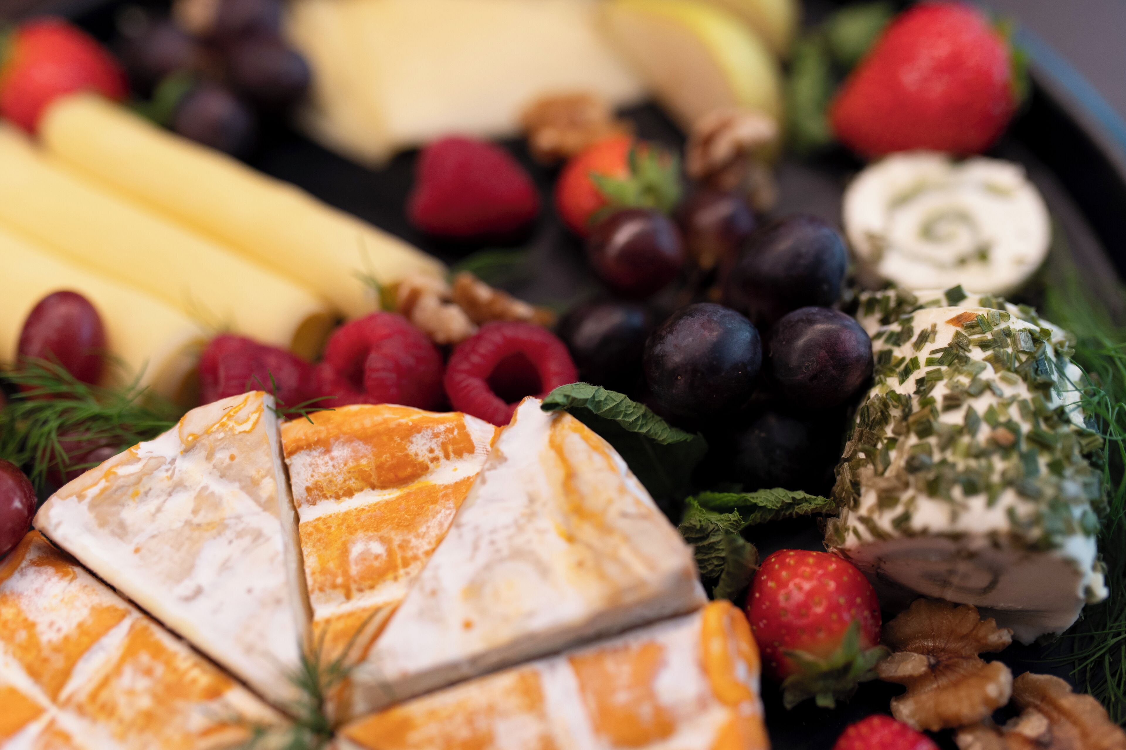 A variety of cheeses, fruits, and nuts arranged on a tray.