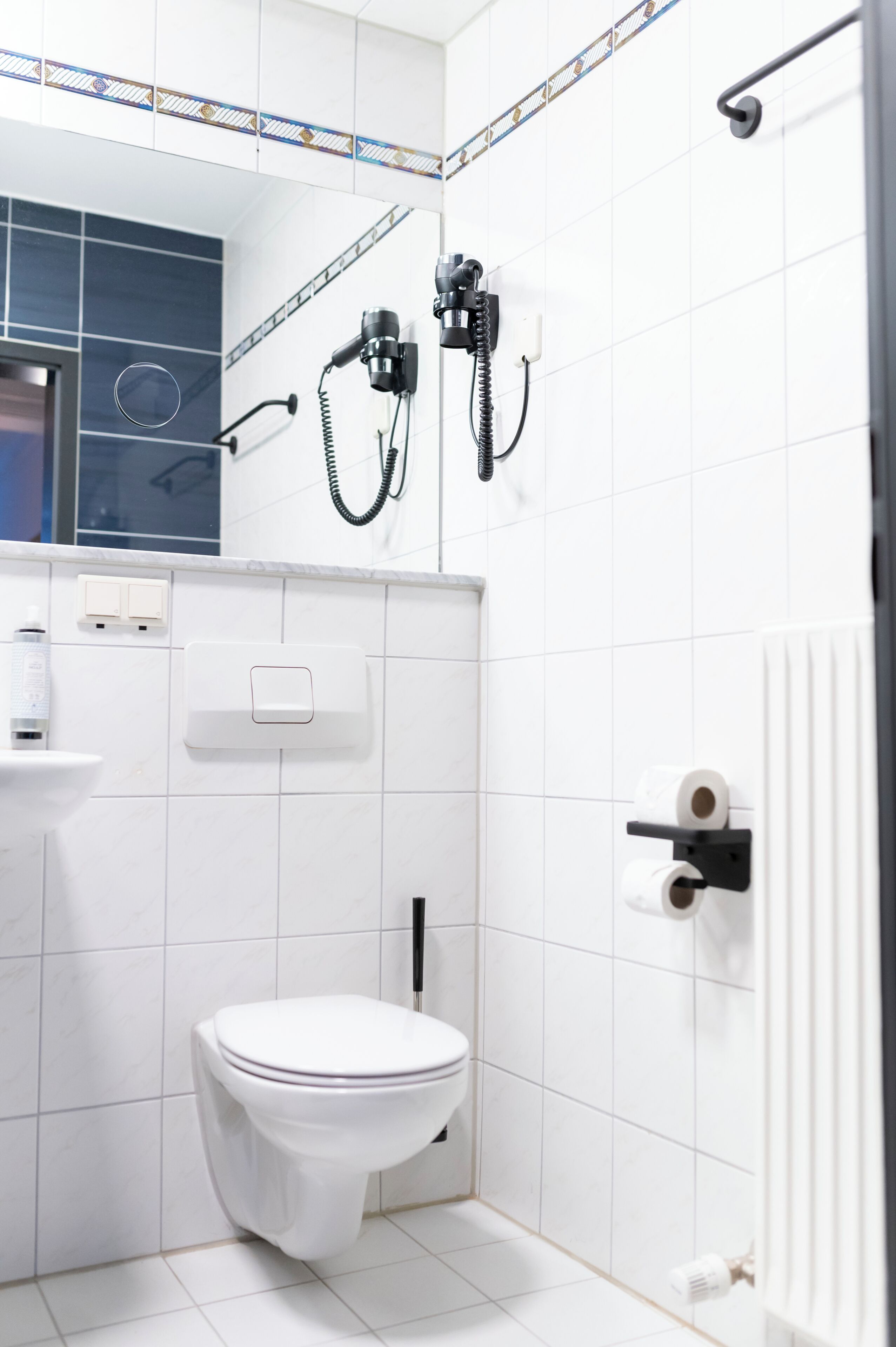 A bathroom with a toilet, a hand dryer, and a paper towel dispenser.