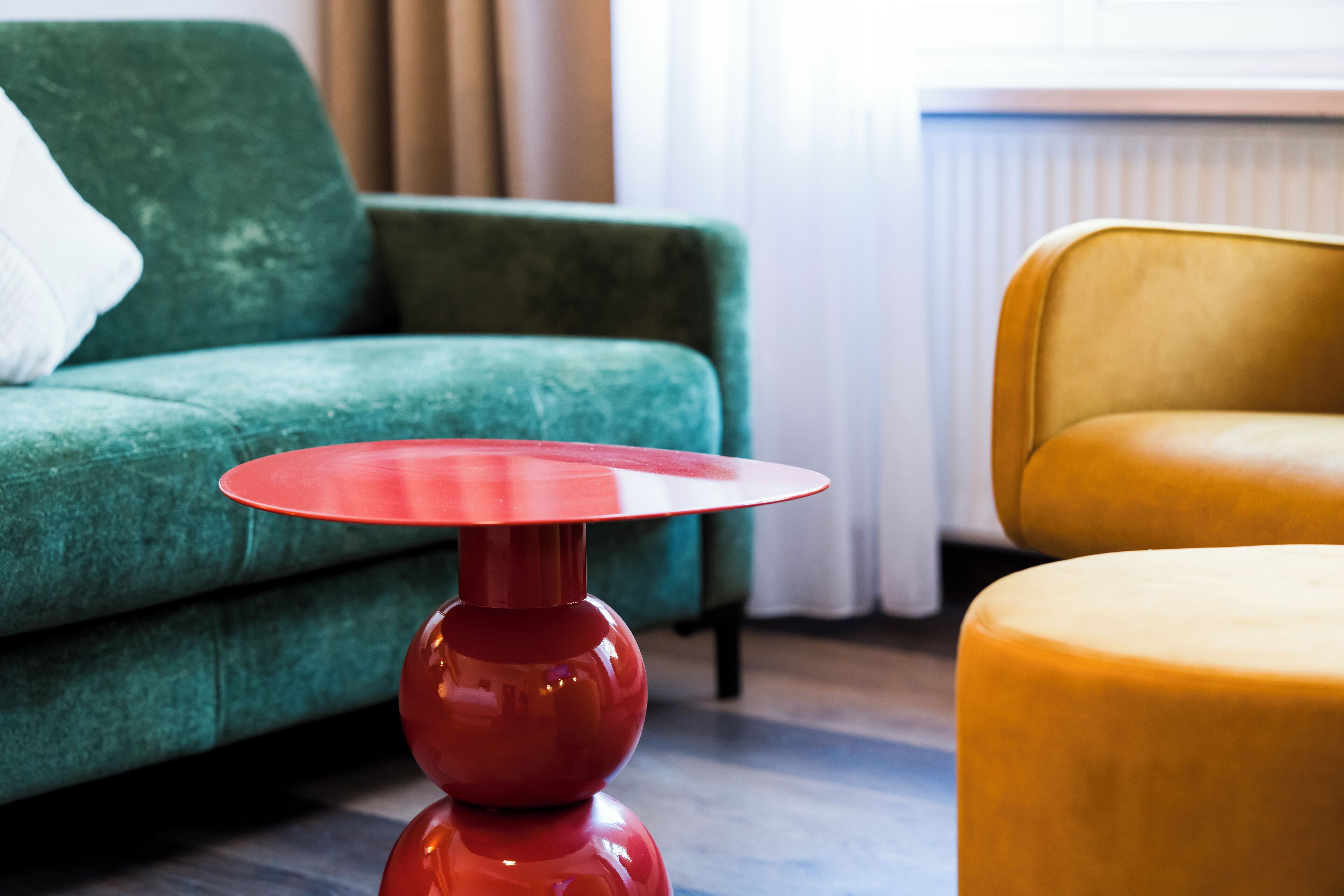 A room with a green sofa, a red table, and a yellow chair.