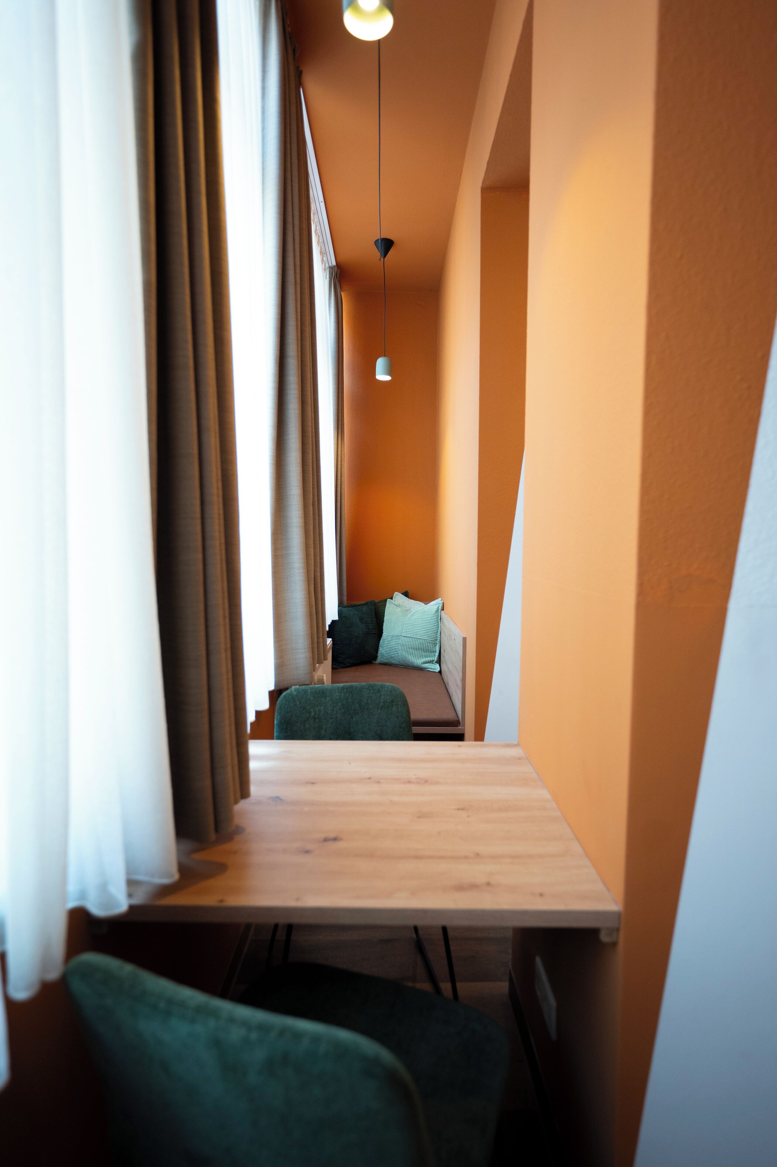 A narrow corridor with a wooden bench, a small table, and a hanging light fixture.