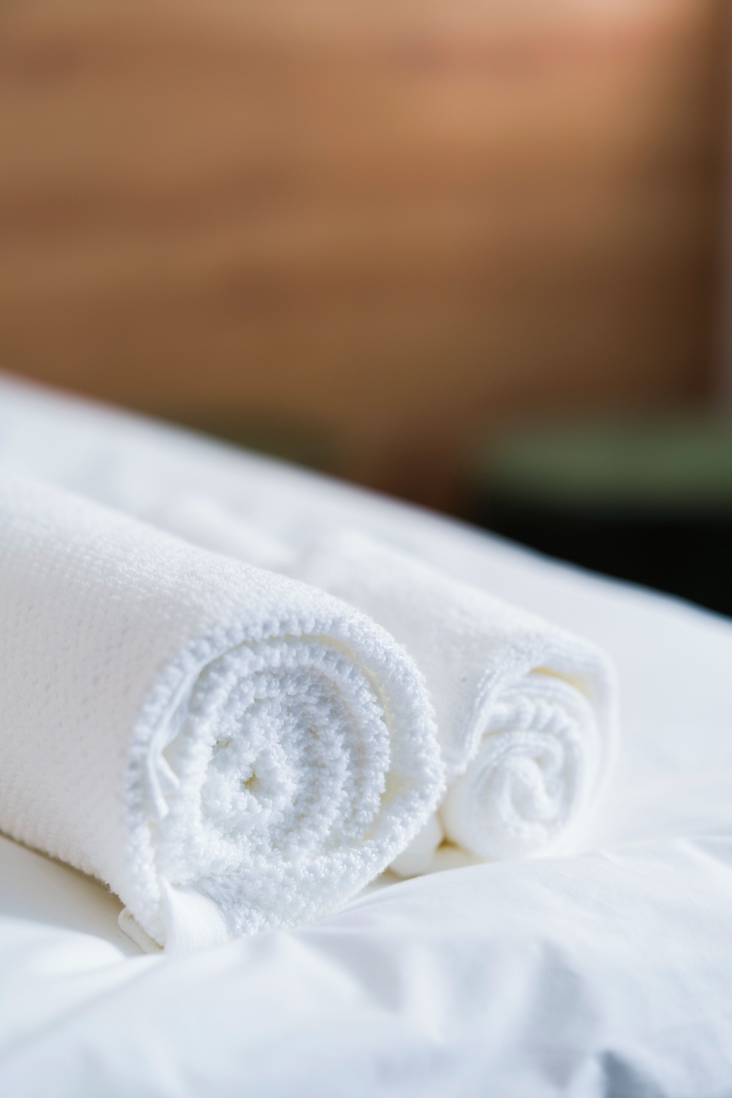 A neatly folded white towel on a bed.