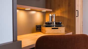 A modern kitchen with wooden cabinetry, a built-in stove, and a television mounted on the wall.