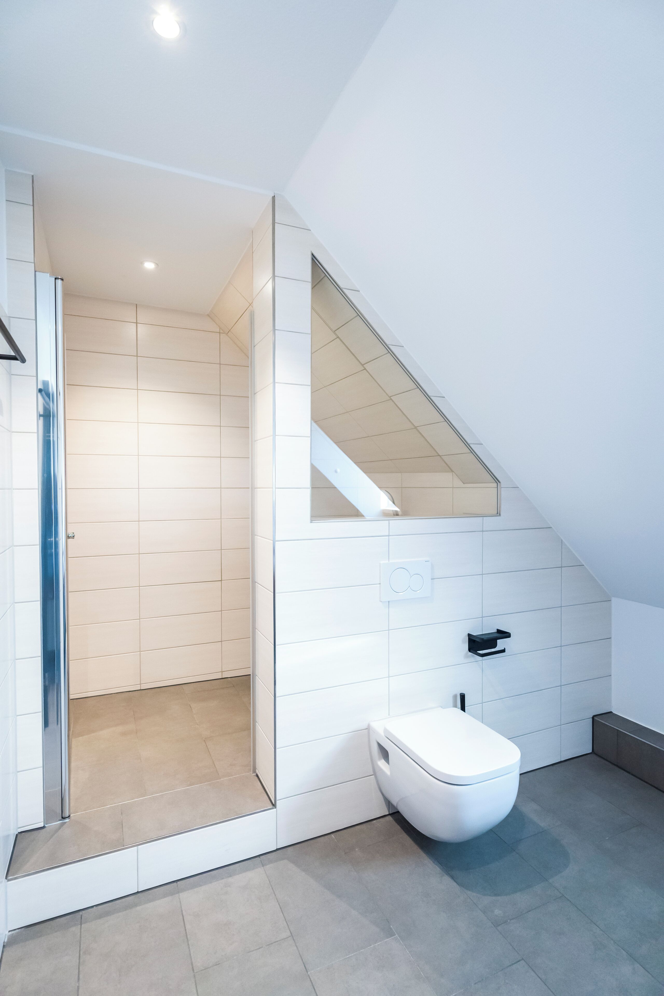 Une salle de bain moderne équipée d’une douche, de toilettes et d’un petit lavabo.