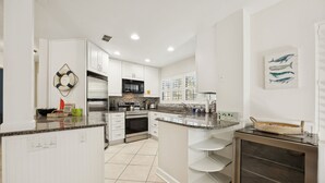 Une cuisine moderne avec des meubles blancs, des plans de travail en granit et un four encastré.