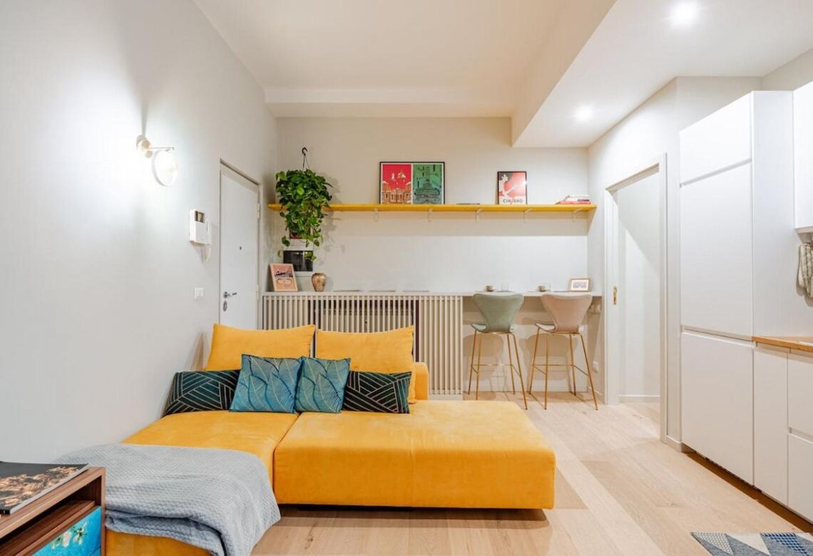 En kompakt opholdsstue med sovesofa, et lille tekøkken og et spiseområde.