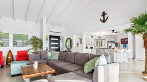 Un salon moderne avec un canapé d’angle, une table basse et un coin repas à l’arrière-plan.