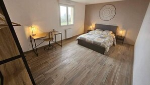 A bedroom with a bed, bedside tables, a desk, and a chair. - New, comfortable bungalow (Les Pieux)