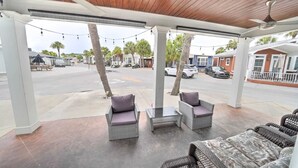 Zona de estar al aire libre con muebles de mimbre y vistas a la calle.