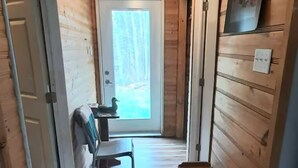 A wooden interior with a bench, a door, and a wall-mounted light fixture.