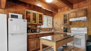 A kitchen with wooden cabinets, a white refrigerator, a stove, and a sink. - Chateau Rouge (Big Bear Lake)
