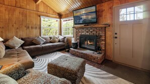A cozy living room with a fireplace, a large TV mounted above it, and a comfortable sofa set. - Chateau Rouge (Big Bear Lake)