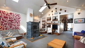 A spacious living room with a fireplace, seating area, and a ceiling fan.