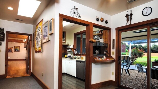 A modern kitchen with white cabinets, a dishwasher, and a dining area with outdoor seating.