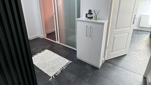 Un interior moderno con un ventanal corredero, un armario blanco con una planta pequeña y un piso de madera oscura.