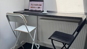 Una habitación pequeña y moderna con un escritorio, dos sillas, una computadora portátil y una taza.